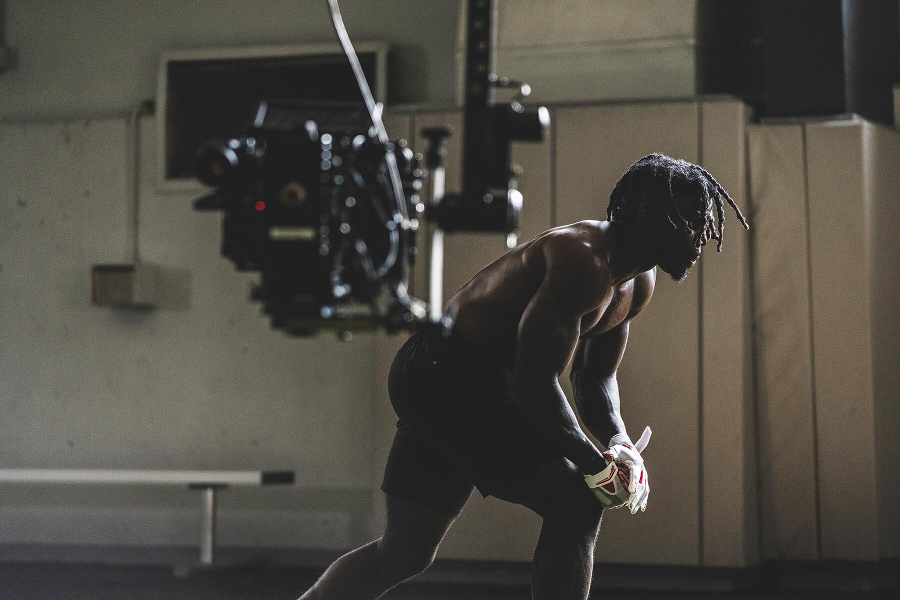 Tyreek Hill is shown wearing shorts and football gloves inside a gym, with professional camera equipment set up by the best production company in Baltimore, Unrivaled, highlighting sports marketing video production for a social media video.