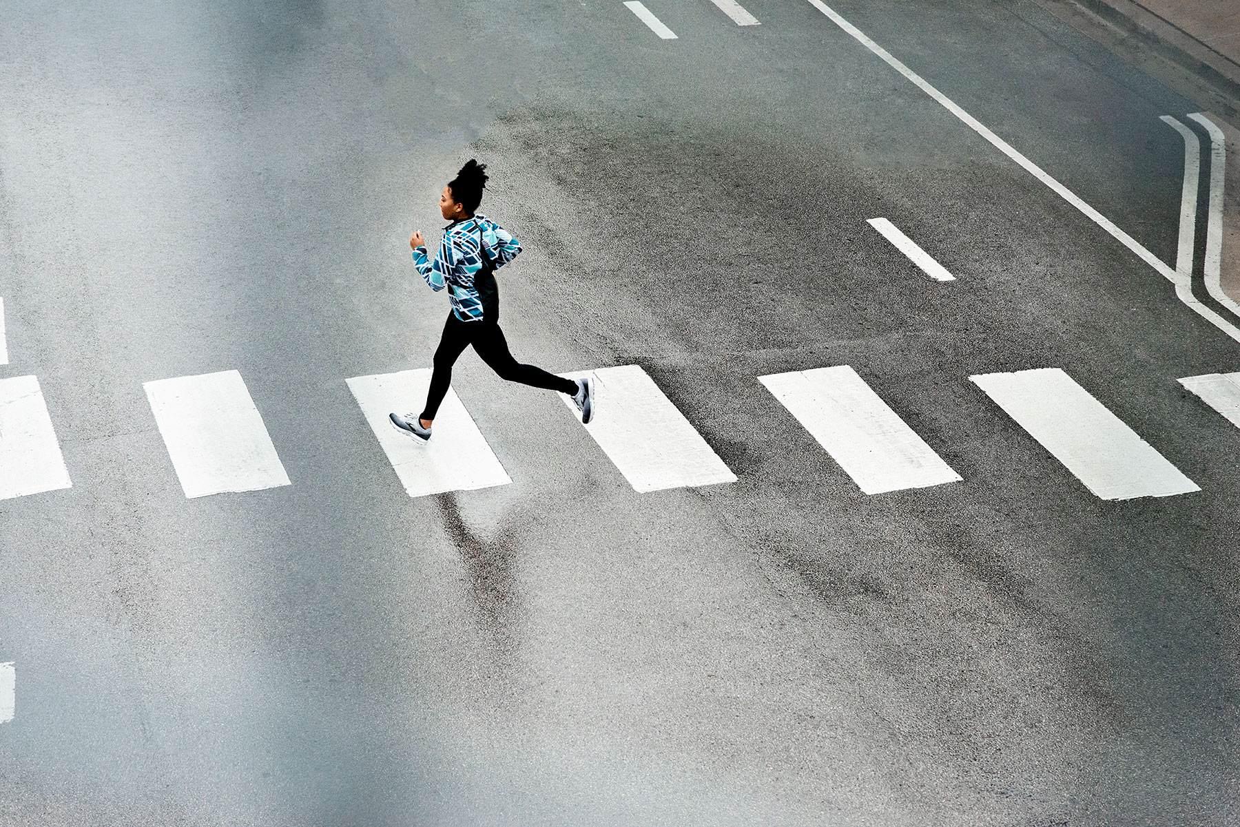 A runner runs across the street in Chicago as part of a fitness and beauty influencer campaign for Brooks Running produced by Unrivaled.