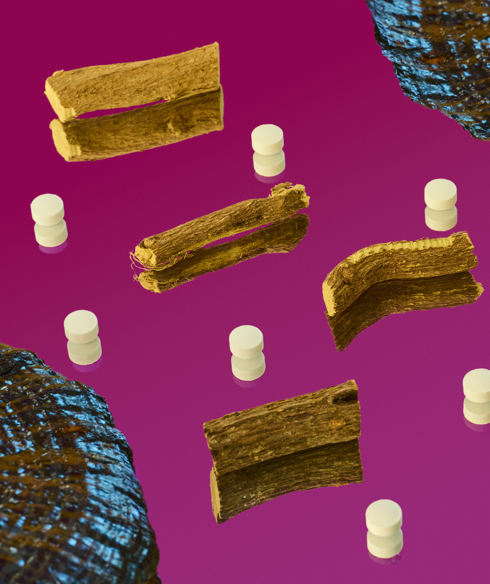 Pills and bark photographed on a reflective surface with bright colors.