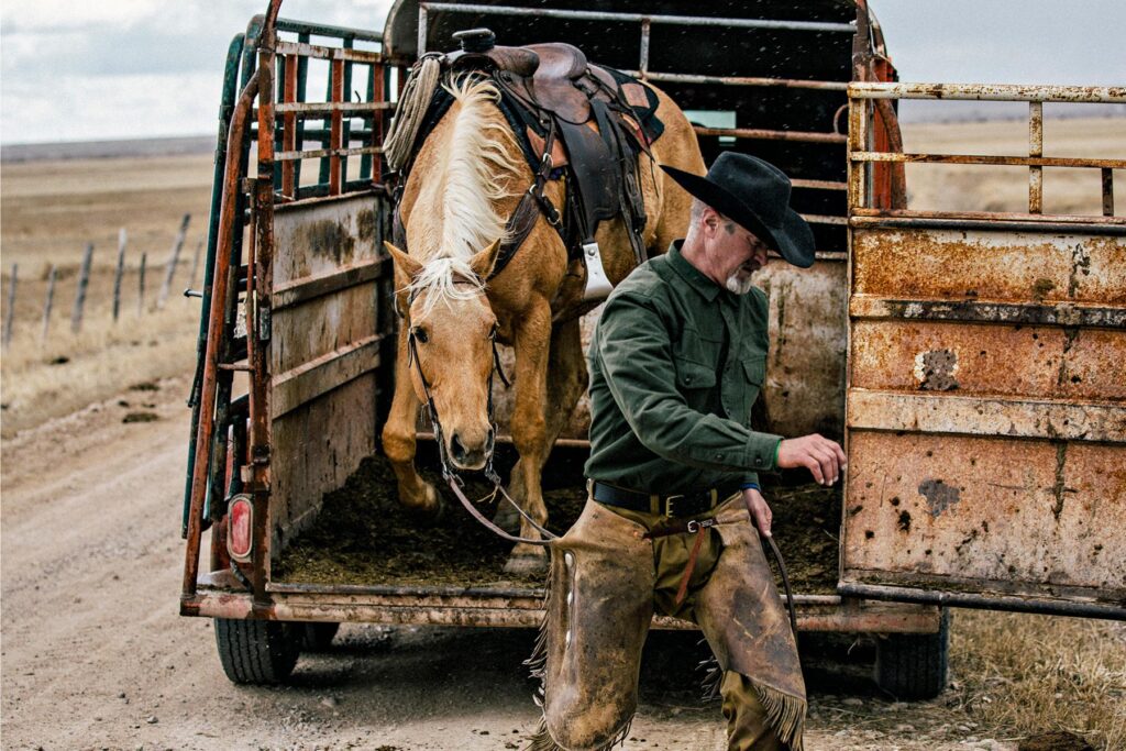 A rancher loads up his horse into a trailer.