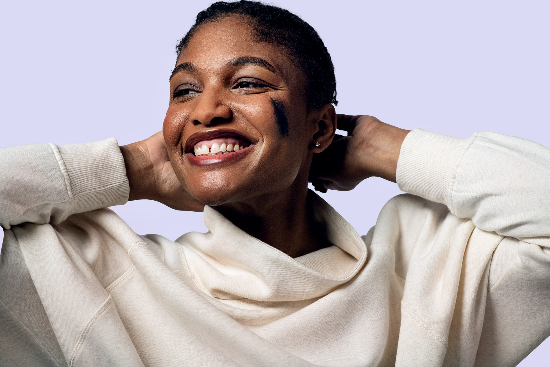 A beautiful African American woman poses for a portrait against a purple background.