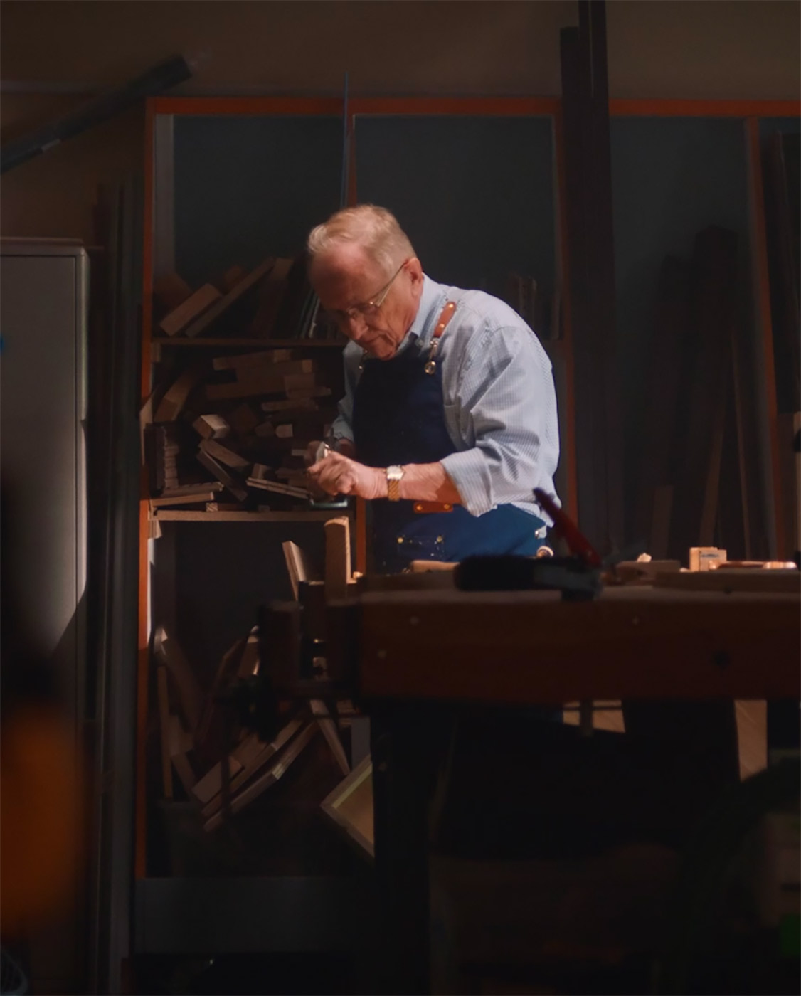 A man in his workshop sanding wood.