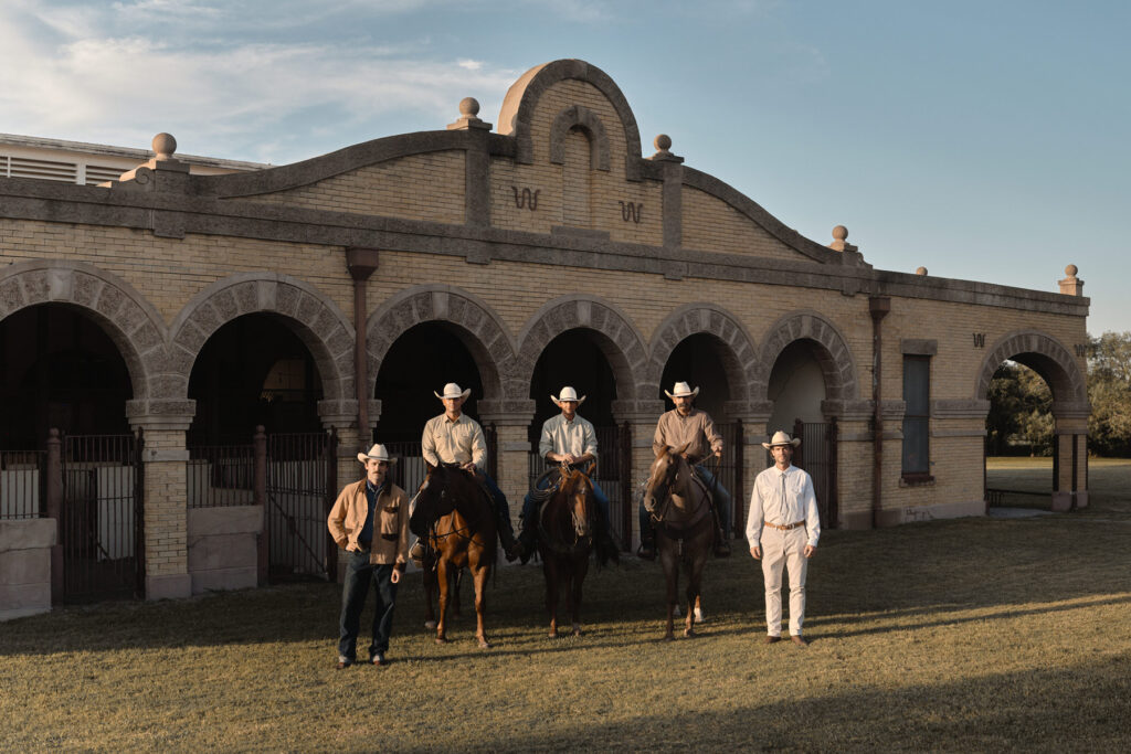 A a group of hunters and ranchers pose for a portrait in front of their stable on their ranch in Texas. Photographed by Travis Gillett.