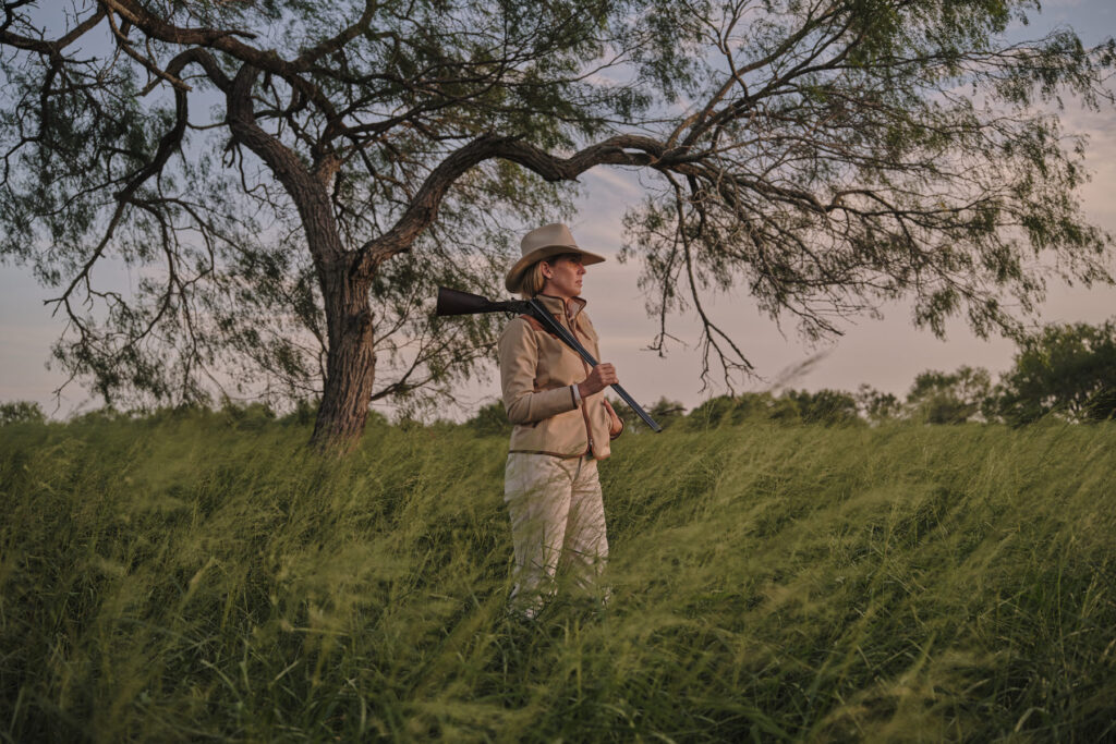 A hunter poses with her rifle and King Ranch Saddle Shop gear in Texas. Captured by photographer, Travis Gillett.