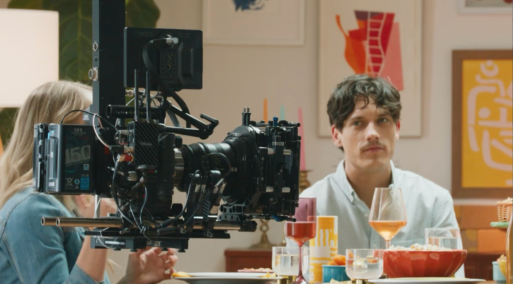 A cinema camera floats on a dolly while working on a commercial set.