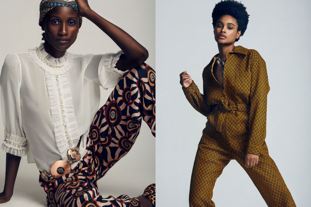 New York City fashion photographer Marquis Perkins photographed Two women pose in stylish outfits against a plain background. The woman on the left wears a white ruffled blouse, printed pants, and a headscarf. The woman on the right wears a brown patterned jumpsuit with a relaxed, confident posture.