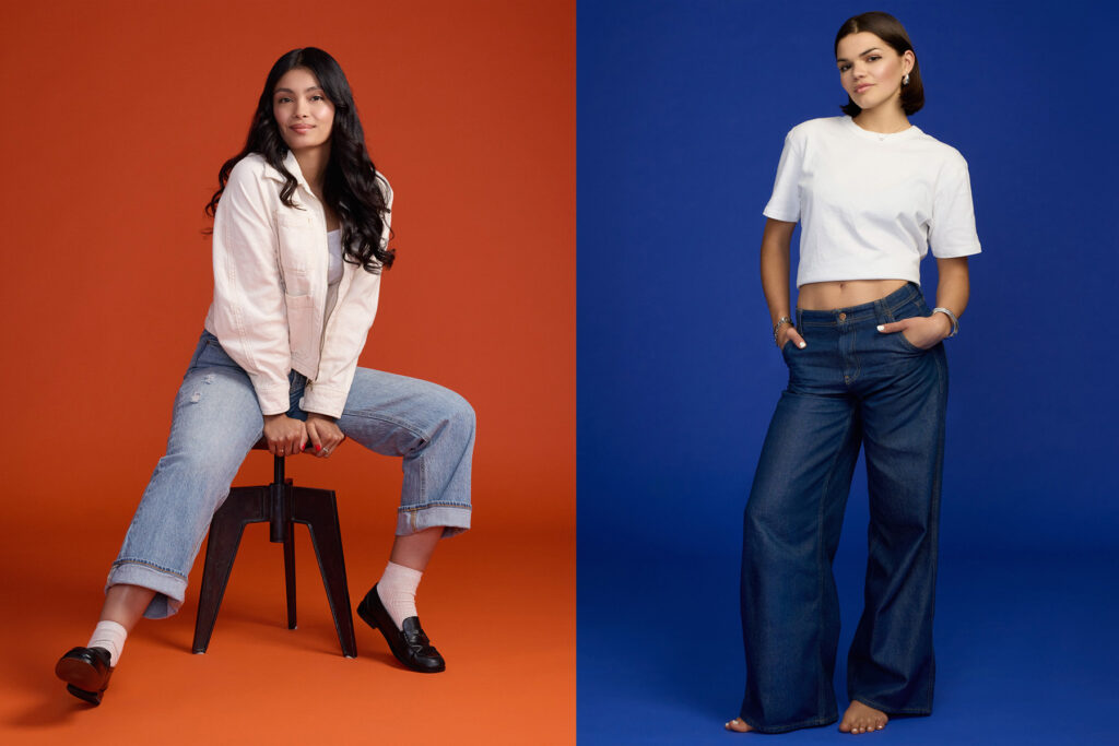 Two women pose against solid backgrounds: one sits on a stool before an orange backdrop, wearing a light jacket and cuffed jeans; the other stands before a blue background, wearing a white crop top and wide-leg jeans.